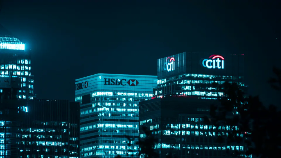 Bank headquarters towers lit up at night in a financial district, representing the choice between mortgage lenders