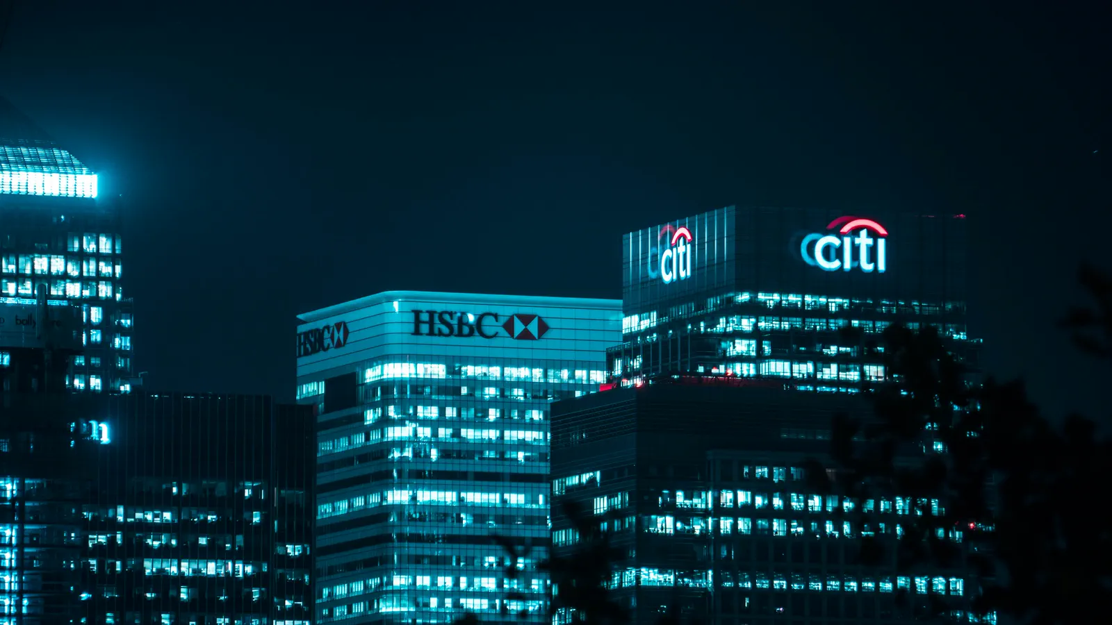 Bank headquarters towers lit up at night in a financial district, representing the choice between mortgage lenders